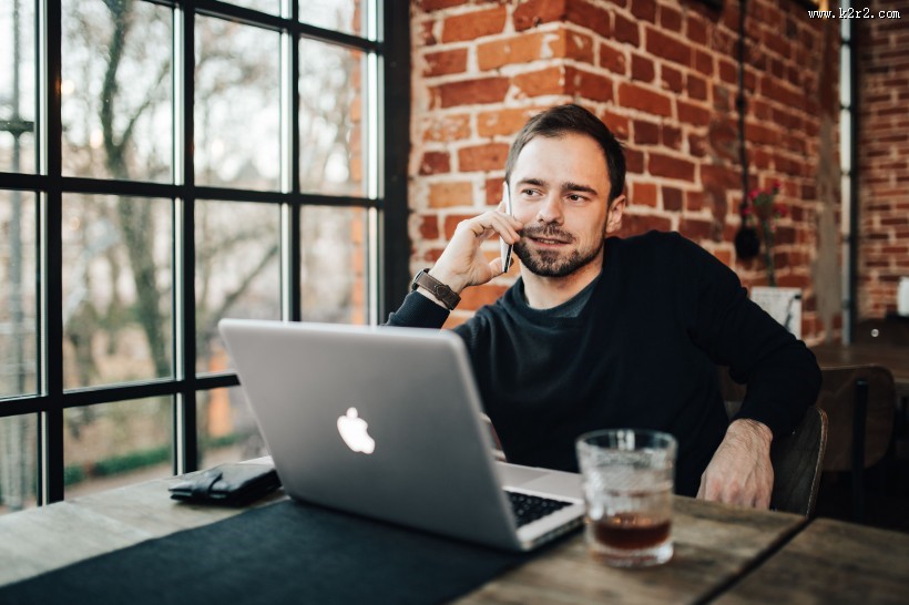 在咖啡厅使用苹果笔记本和手机的年轻男子图片