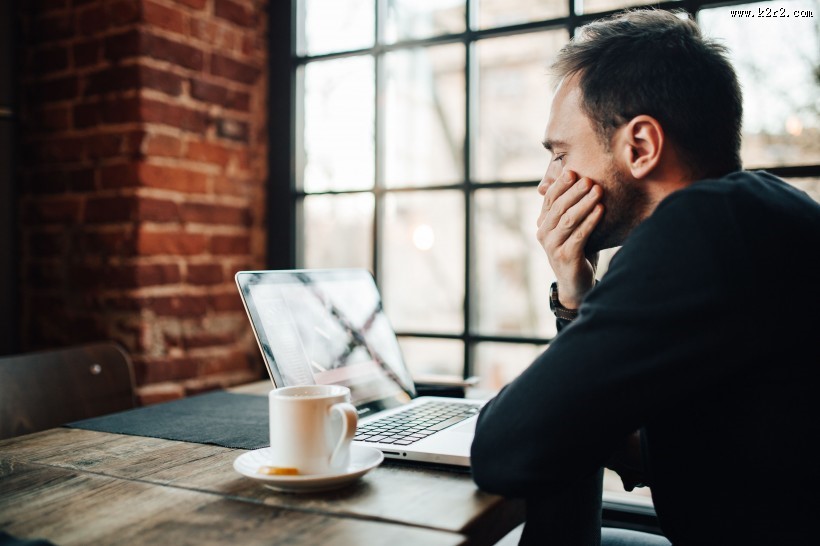 在咖啡厅使用苹果笔记本和手机的年轻男子图片