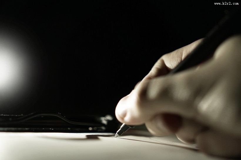 拿着笔书写的图片