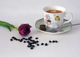 咖啡豆散落在装有咖啡的杯子旁图片大全